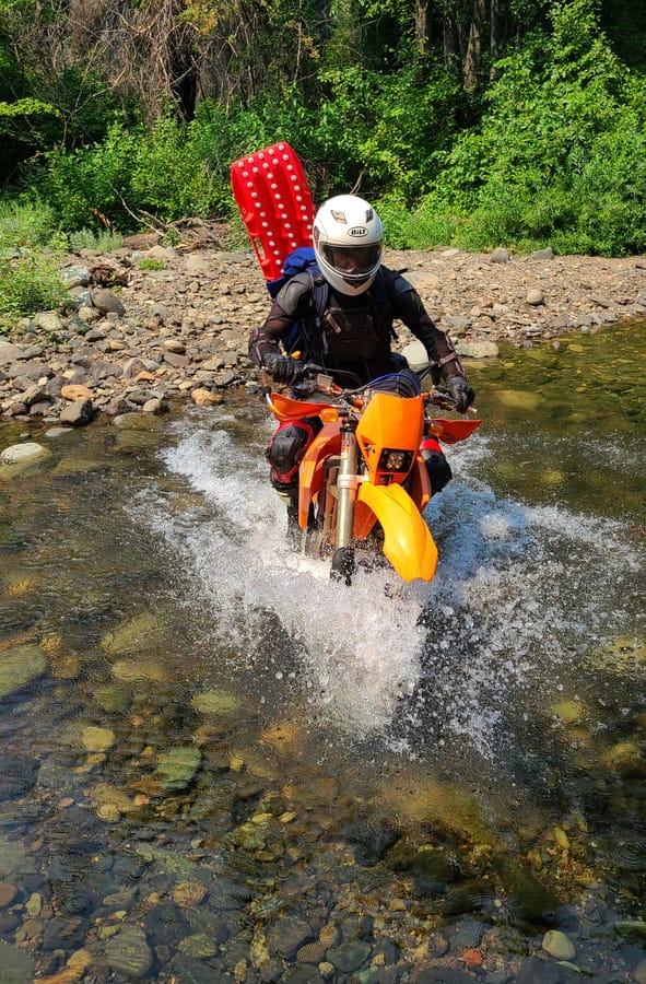rider crossing a creek on a motorcycle