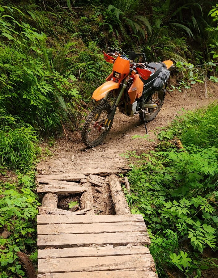motorcycle parked in front of a broken bridge