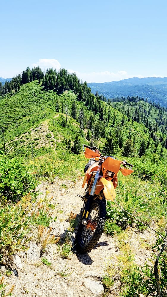 motorcycle parked on a trail going along a mountain ridge