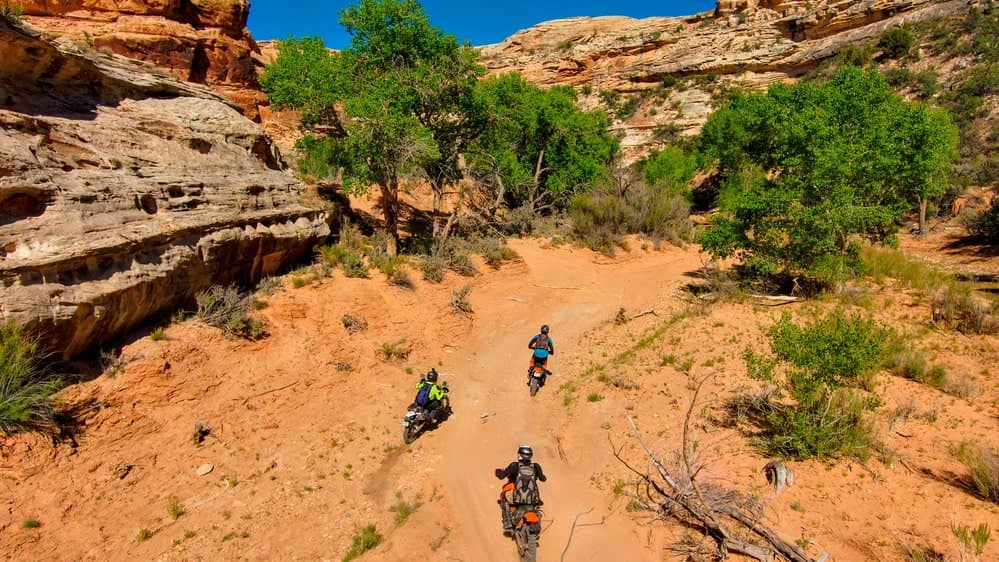 three riders going through a sand wash