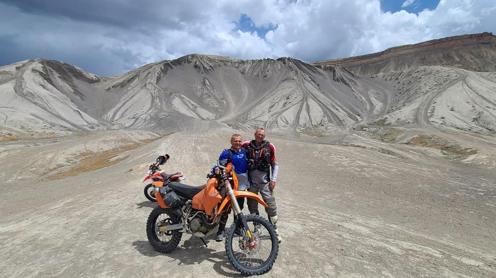 two riders posing next to a bike and steep hill climb