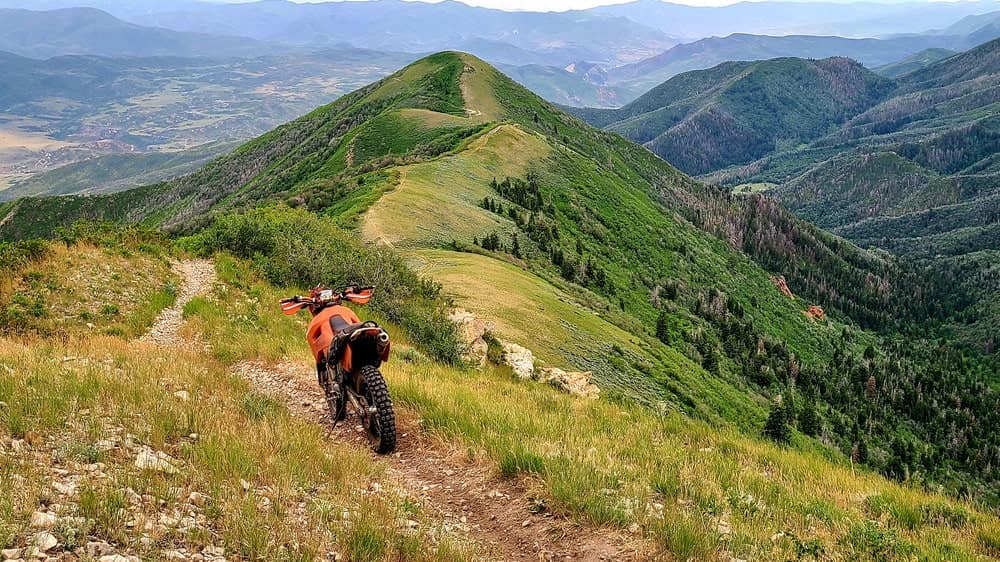 motorcycle parked atop a ridge with trail continuing into the distance