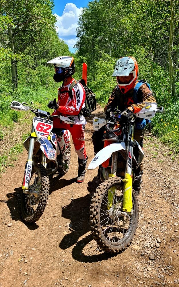 two riders on motorcycles with chain saws