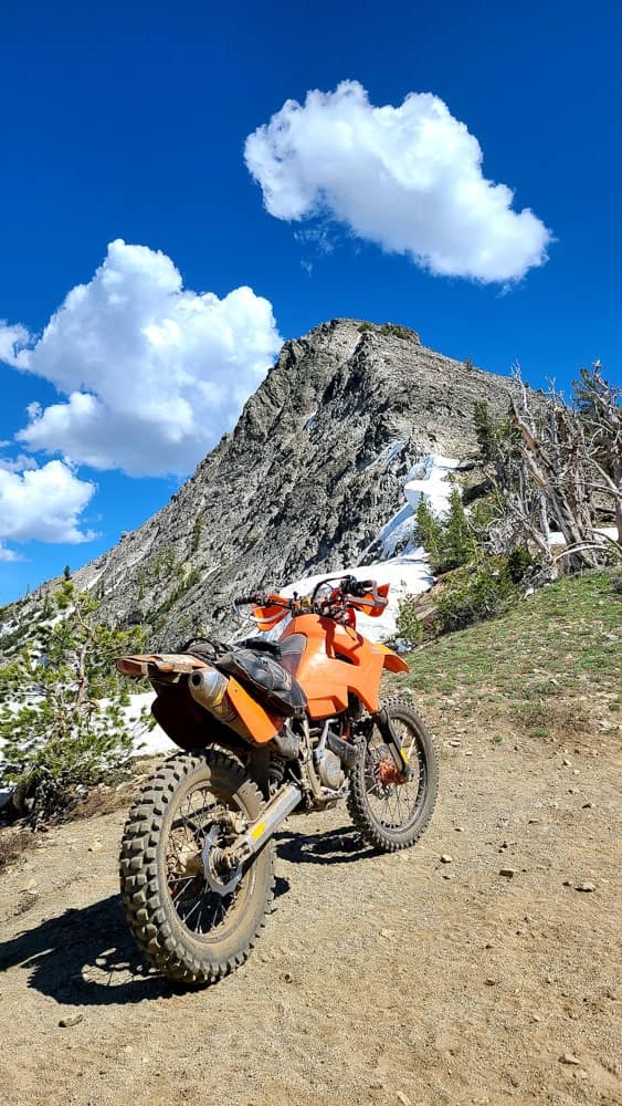 a motorcycle parked with clouds just above the peak next to it