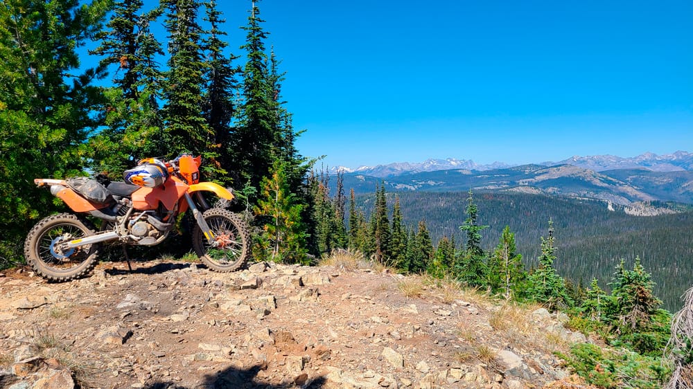 motorycle parked on a ridge with snowy peaks behind