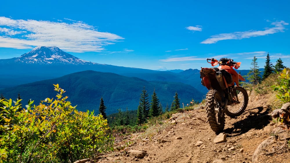 motorycle parked on a trail with a snowy mountain behind it