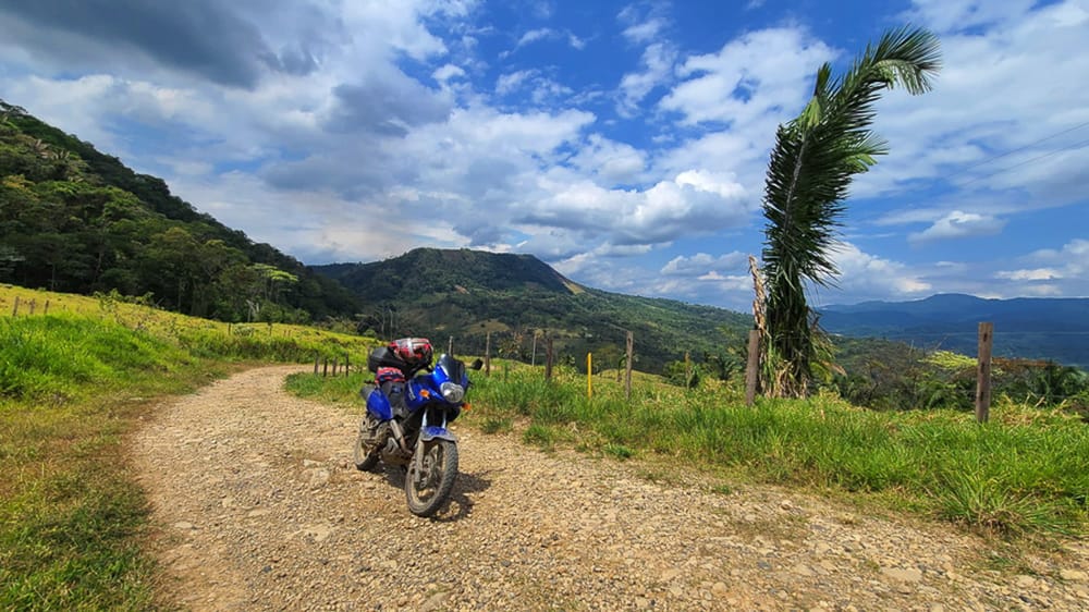 motorcycle on a dirt road with green valley behind 