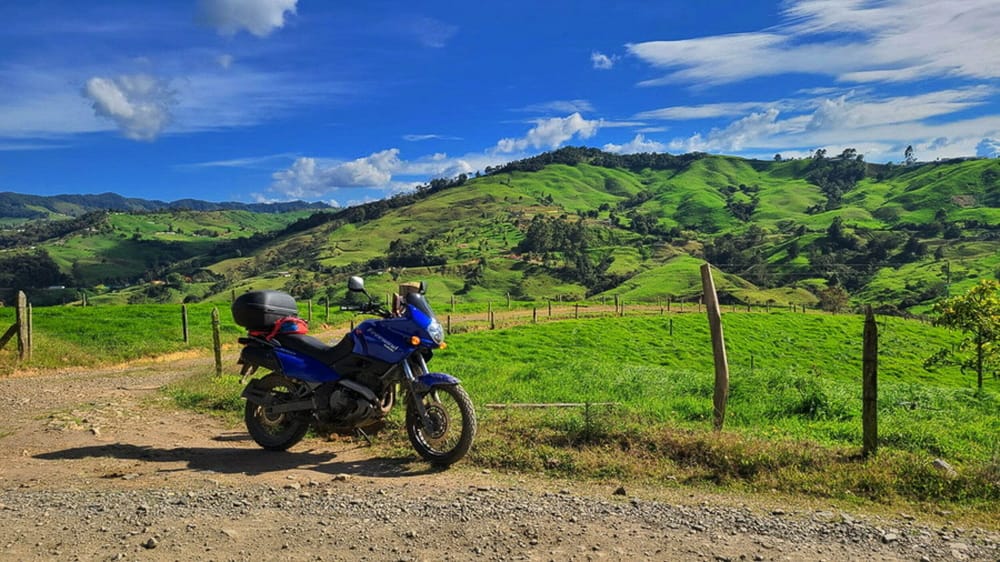 motorcycle parked on a dirt road with green hills behind