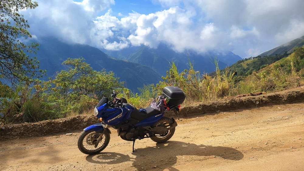 motorcycle parked on a dirt road high up in mountains