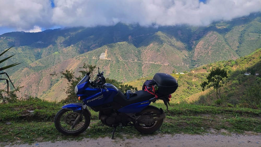 motorcycle parked on a dirt road with steep mountain slopes behind