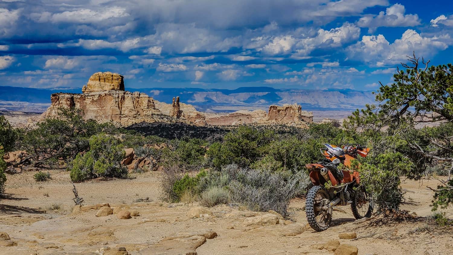motorcycle parked on yellow rock with desert scenery behind
