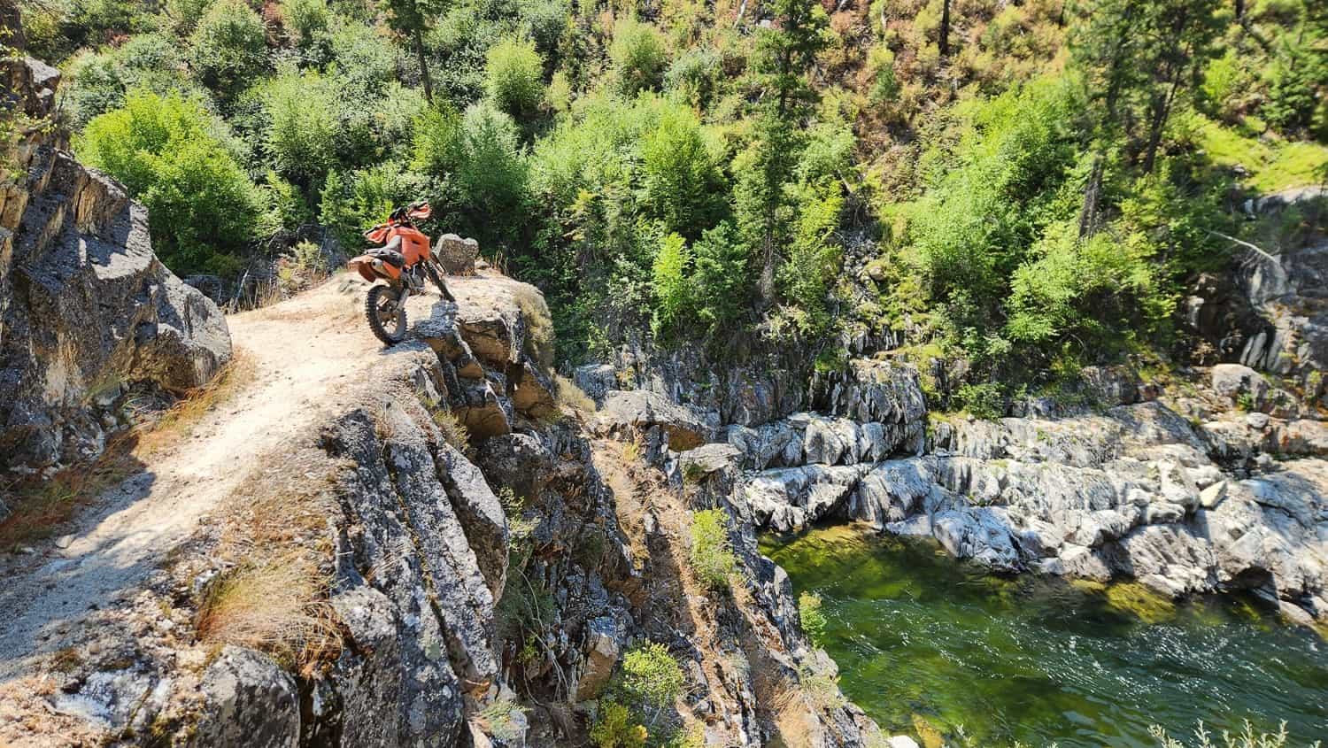 motorcycle on a trail hugging cliffs high above a river