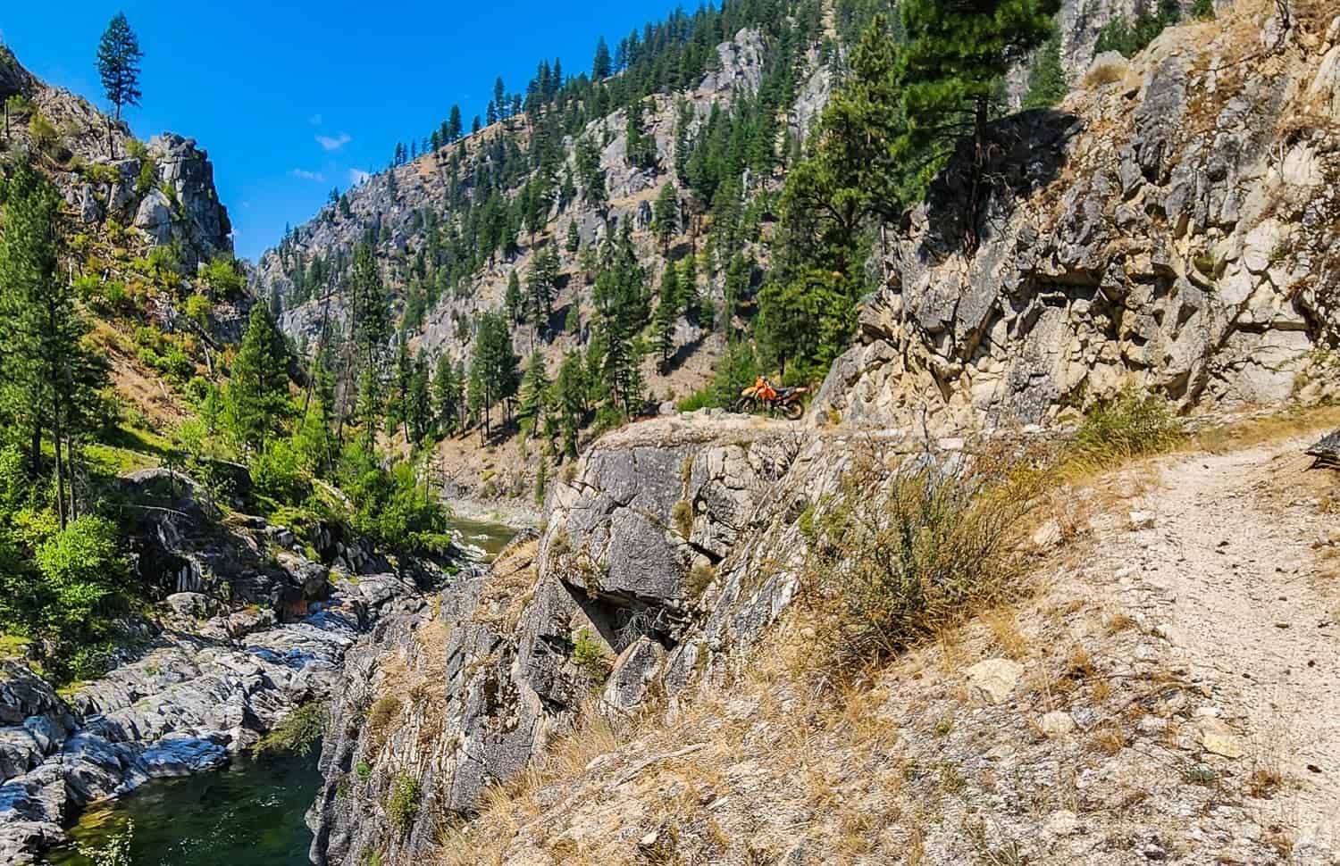motorcycle at the edge of a cliff high above a green river