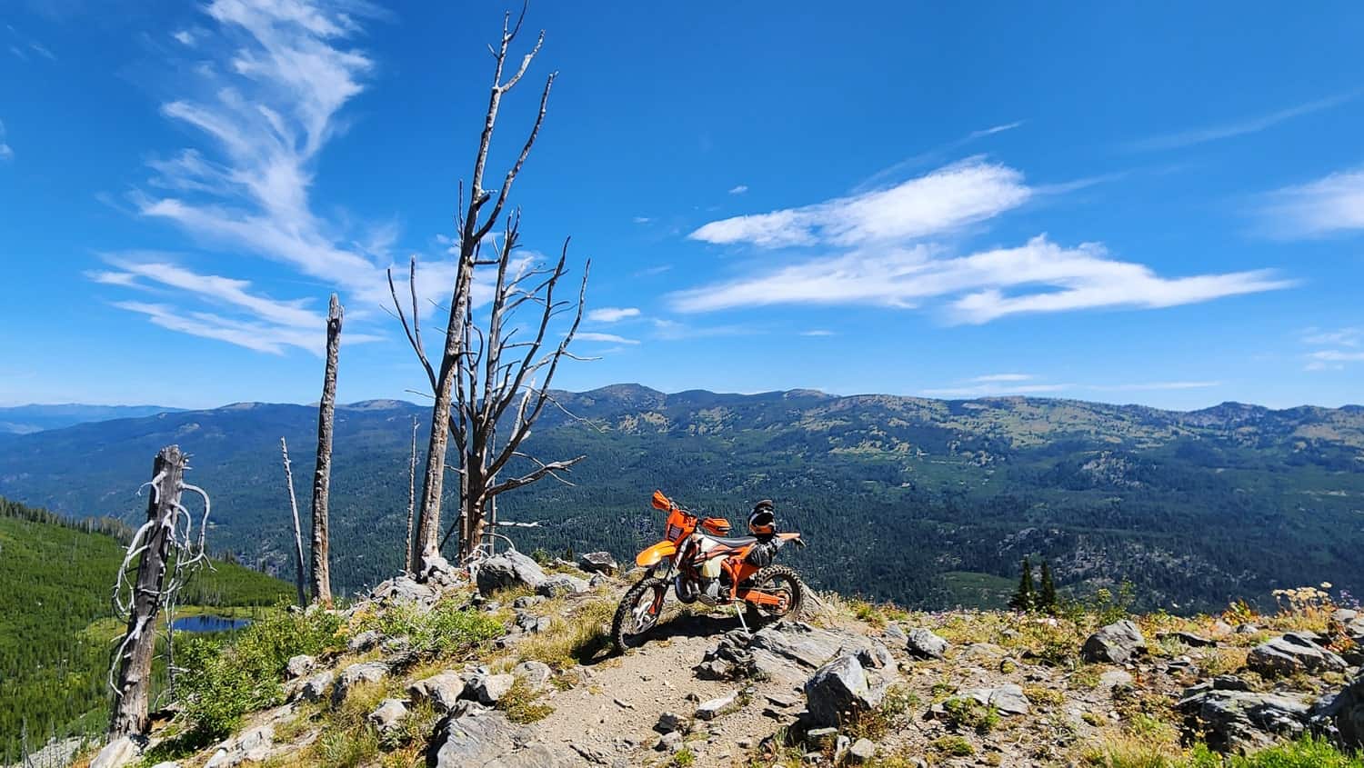 motorcycle on a mountain ridge with a lake and valley behind