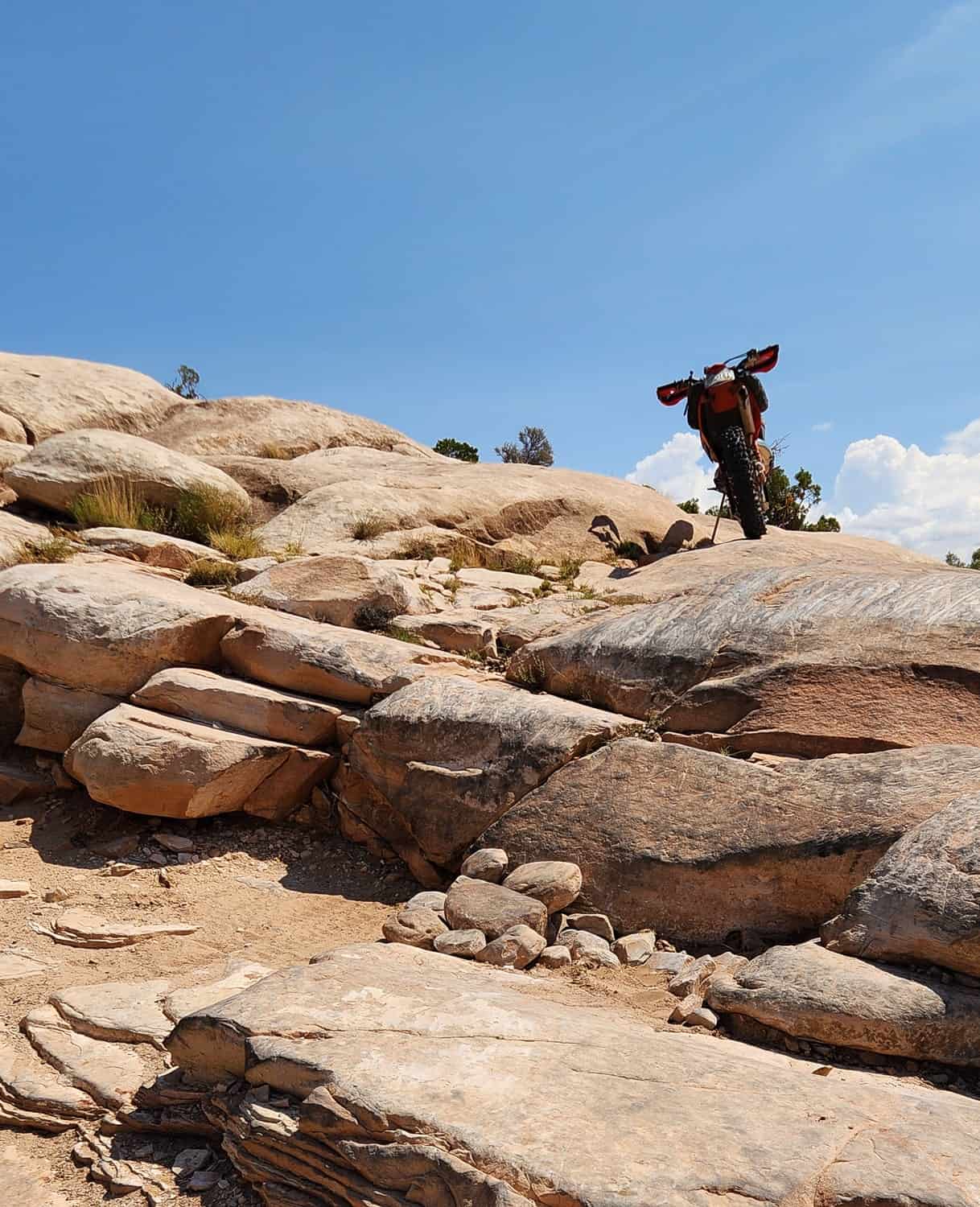 a rider sitting atop a cliff with motorcycle next to him