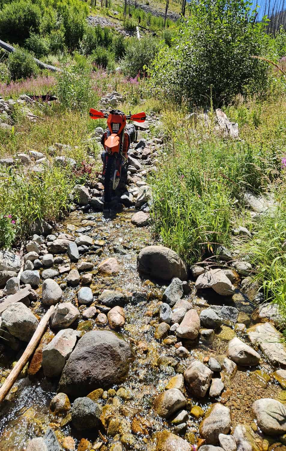 motorcycle on a trail running through a rocky creek