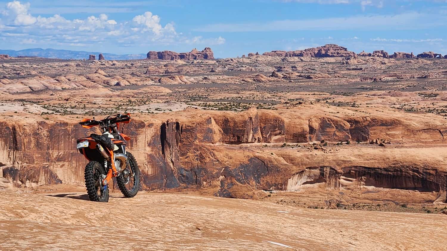 motorcycle on slickrock with canyons behind it