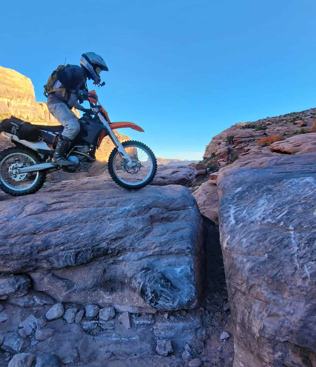 rider on a motorcycle about to go over an gap between two rocks