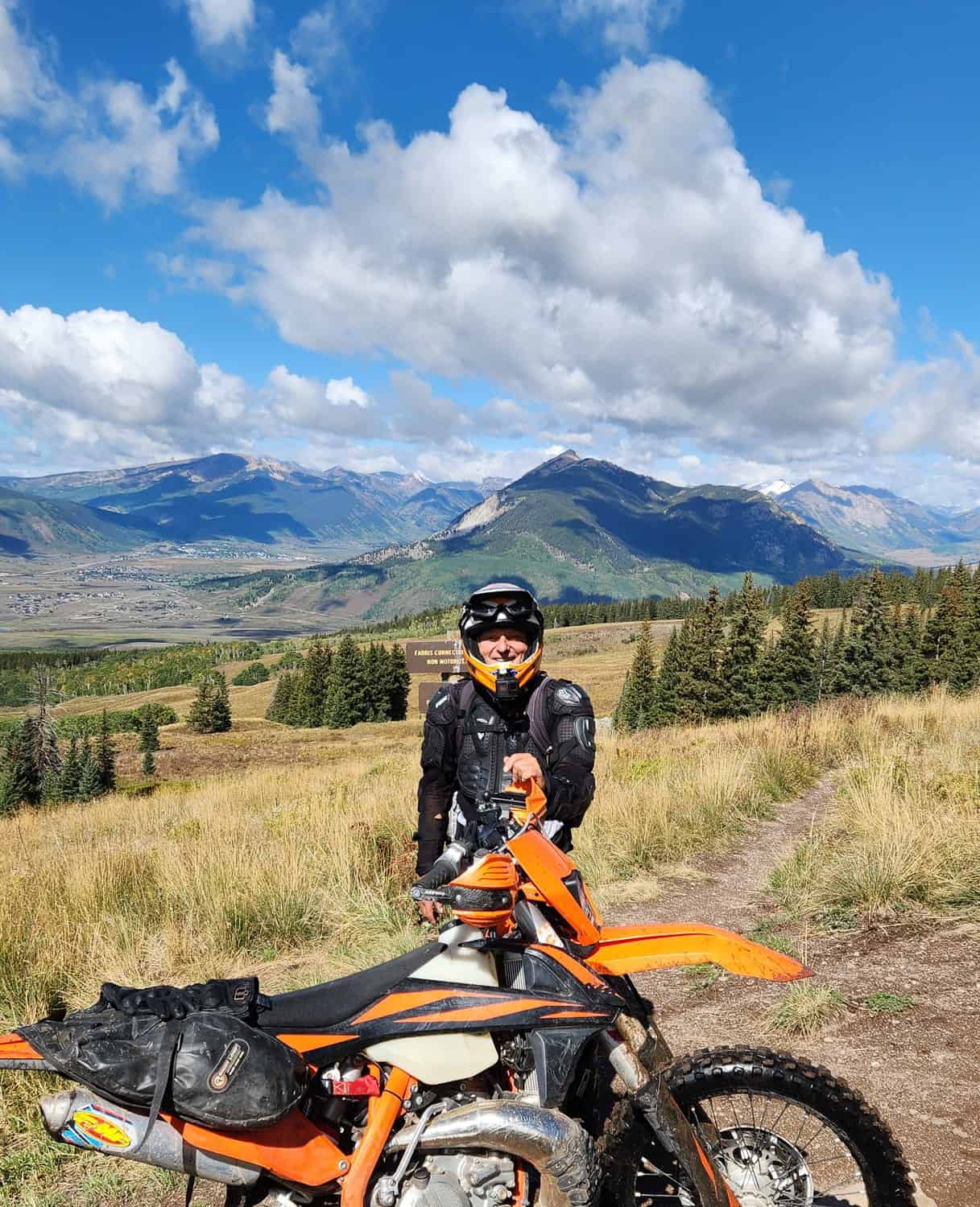 rider and motorcycle with a town in a valley behind