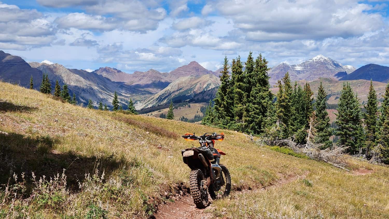 motorcycle in a meadow with high peaks behind
