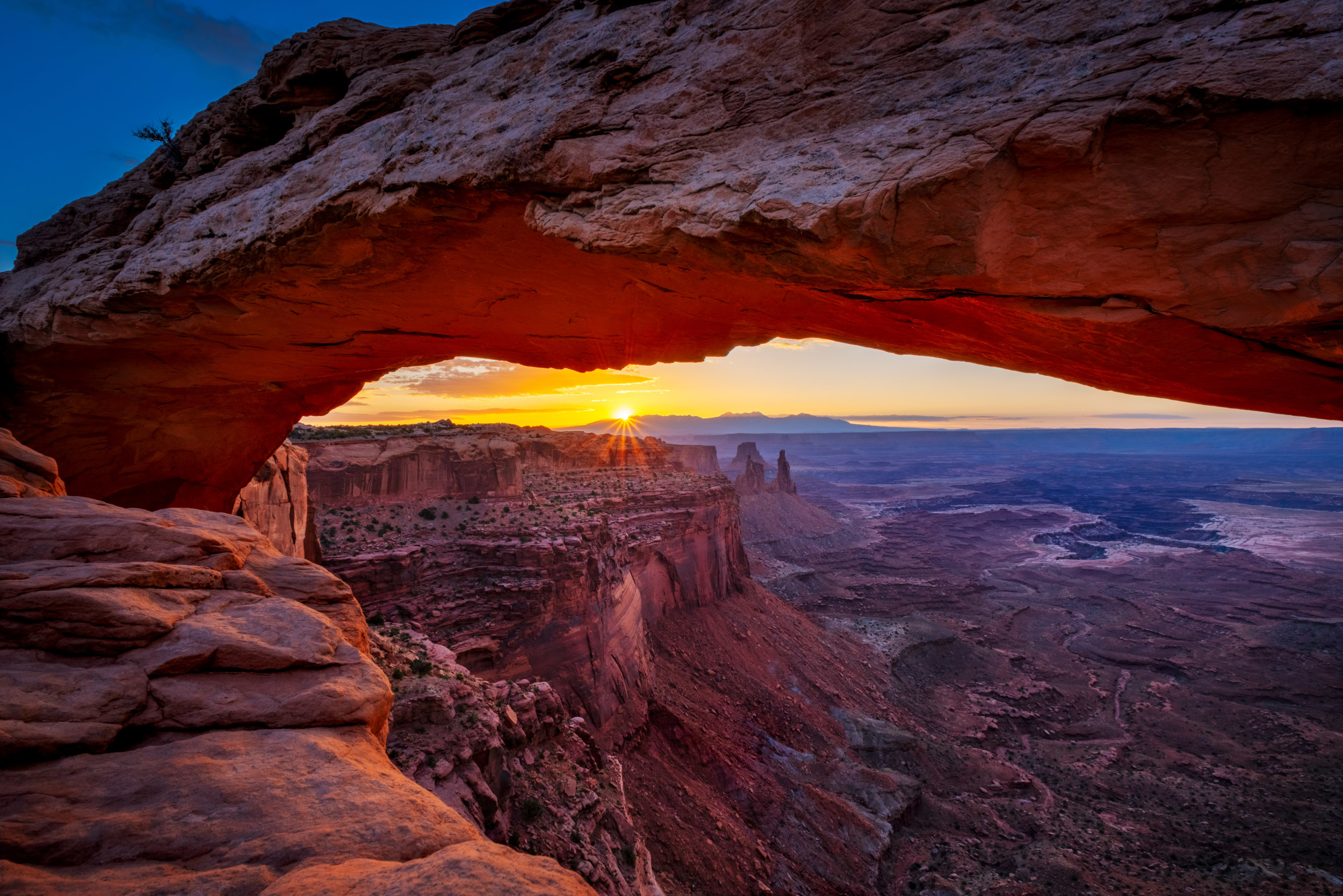 a view of the white rim and rock spires next to it from an arch