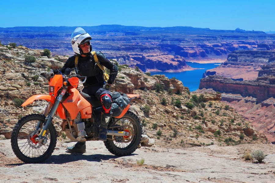 rider on his motorcyc le with a lake and mesas behind