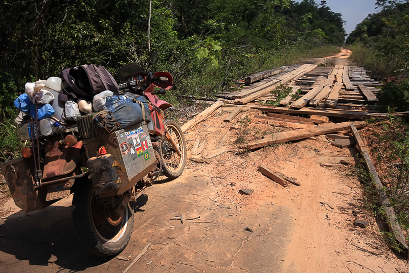 overloaded motorcycle with a broken bridge in front