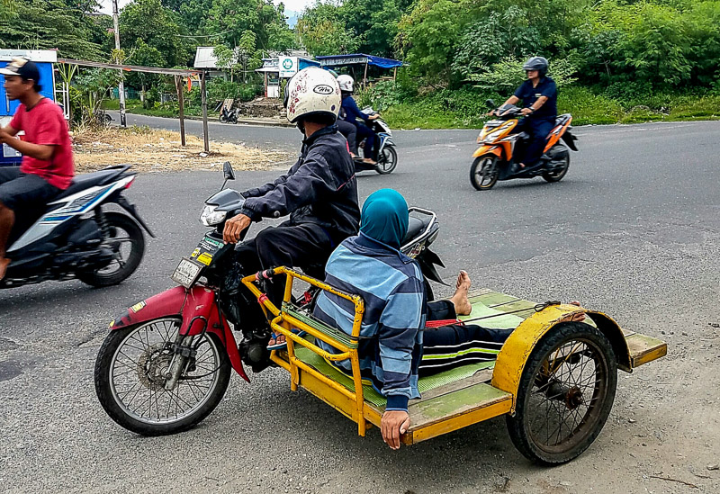 lady riding sidecar with no seat, just flat wooden surface
