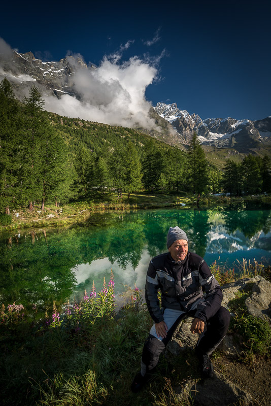 posing by a lake with high mountains behind