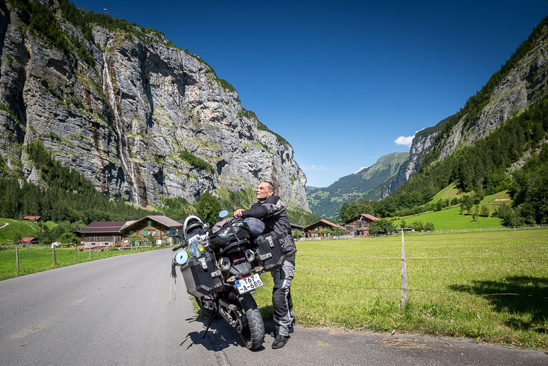 motorcycle parked in a green valley with steep walls and waterfalls