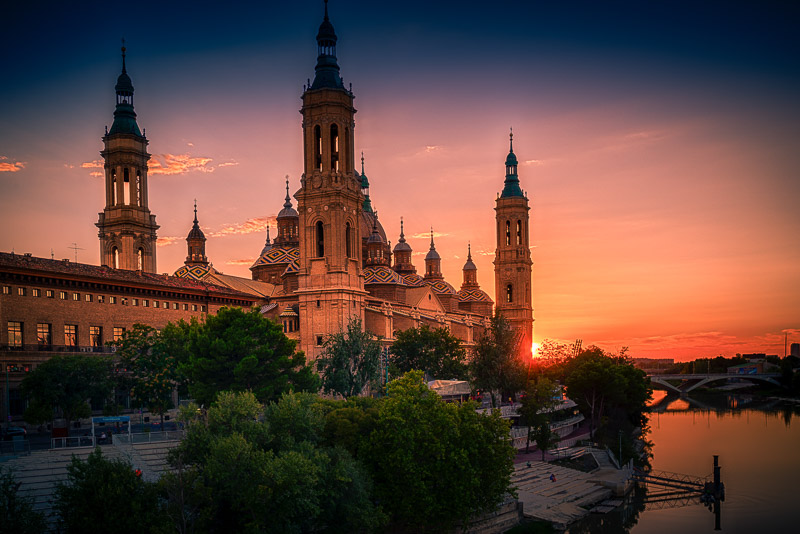 Red sky behind a big cathedral with a bridge in front
