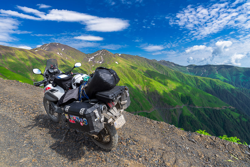 motorcycle parked on a dirt road near the crest of a mountains