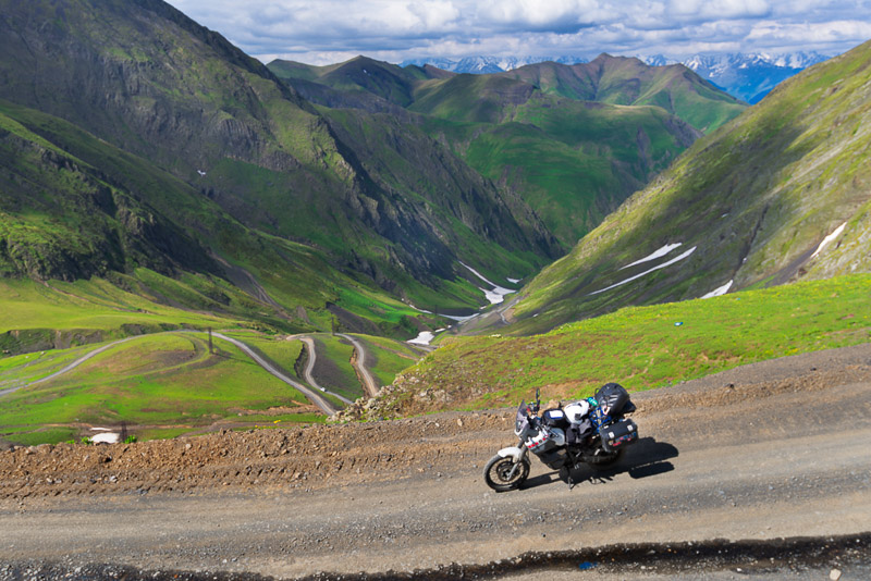 motorcycle parked on a dirt road with switchbacks below