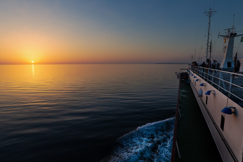 ferry heading towards the setting sun