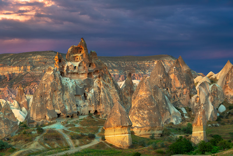 Carved out, giant cone-shaped rocks with dark sky behind 