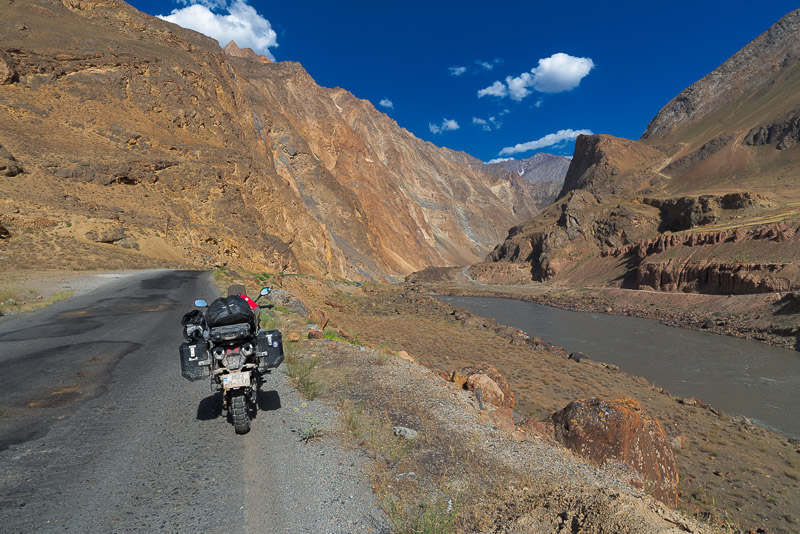 motorcycle parked on a road going up a valley with baren rock walls on both sides