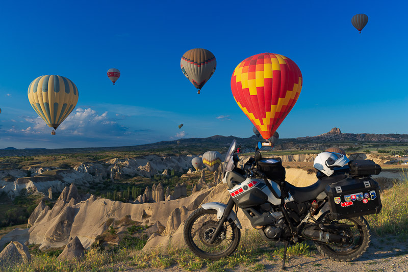 motorcycle parked with numberous baloons in the background