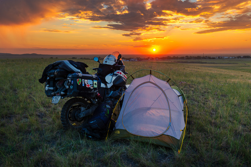 motorcycle and tent with setting sun behind