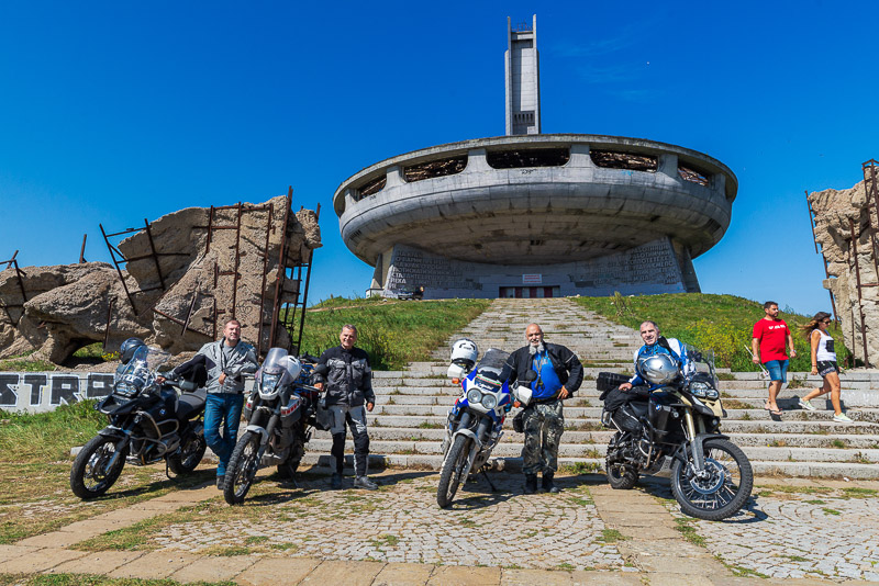 posing with fellow riders in front of a communist-era monument