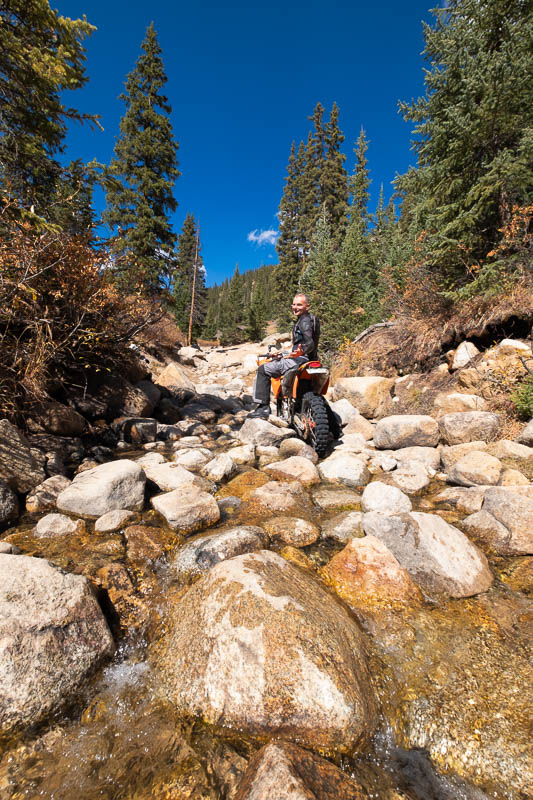 motorcycle and rider in a creek among big rocks