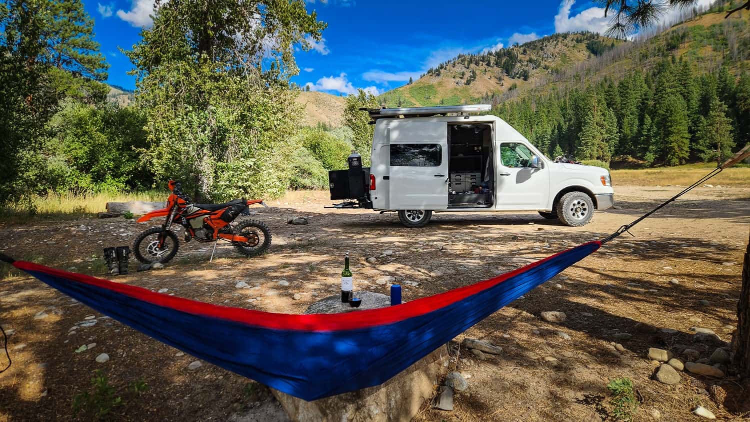 camp with van and hammoc and dirt motorcycle