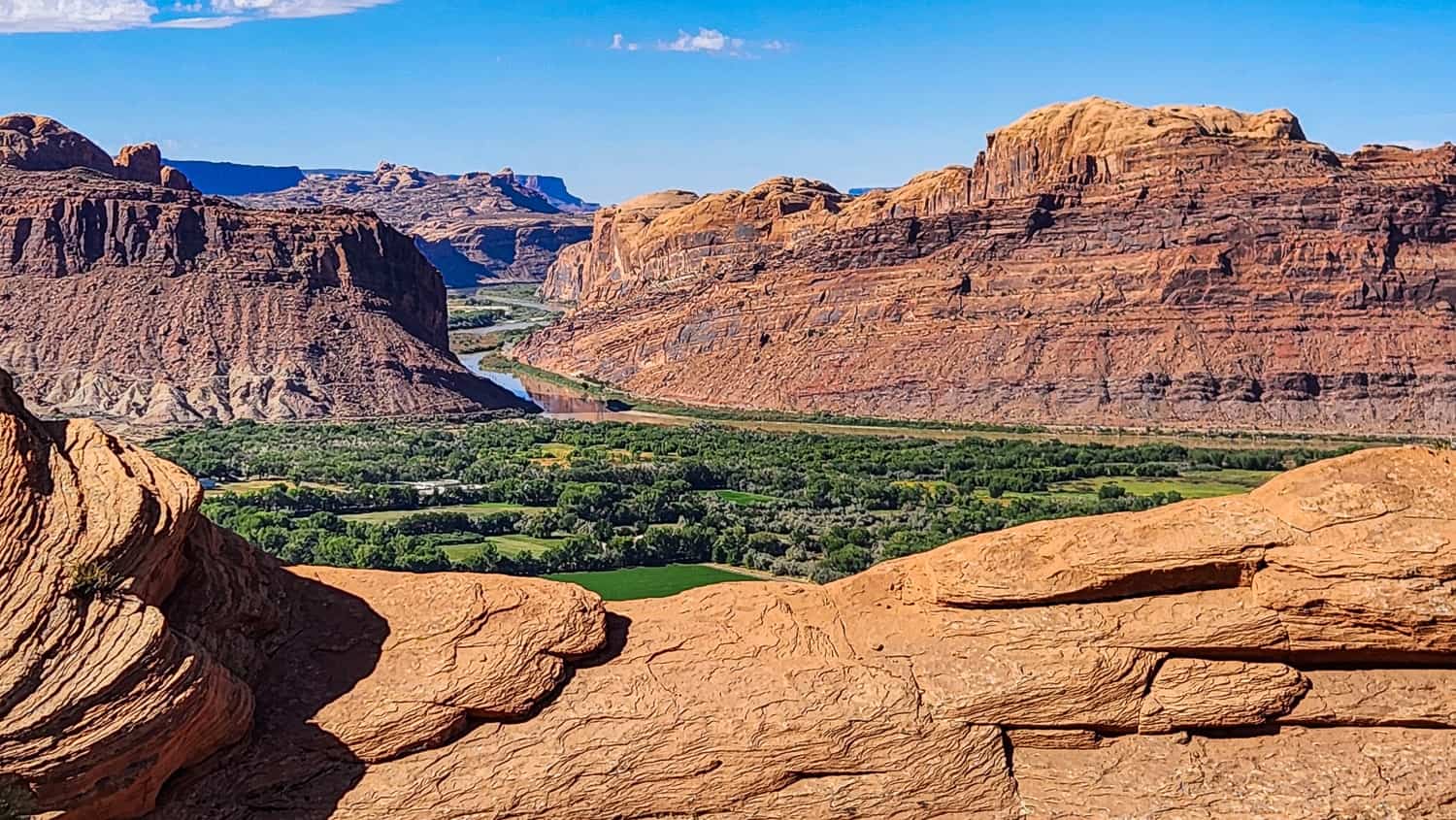 view of a green valley and river going through a canyong beyond the valley 
