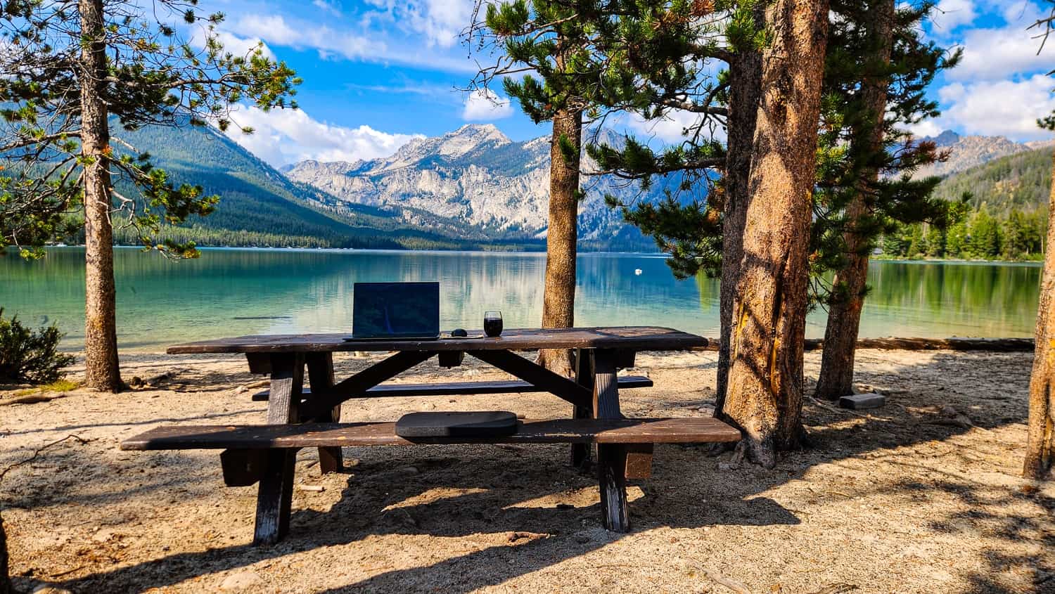 laptop on a picnic table next to a lake