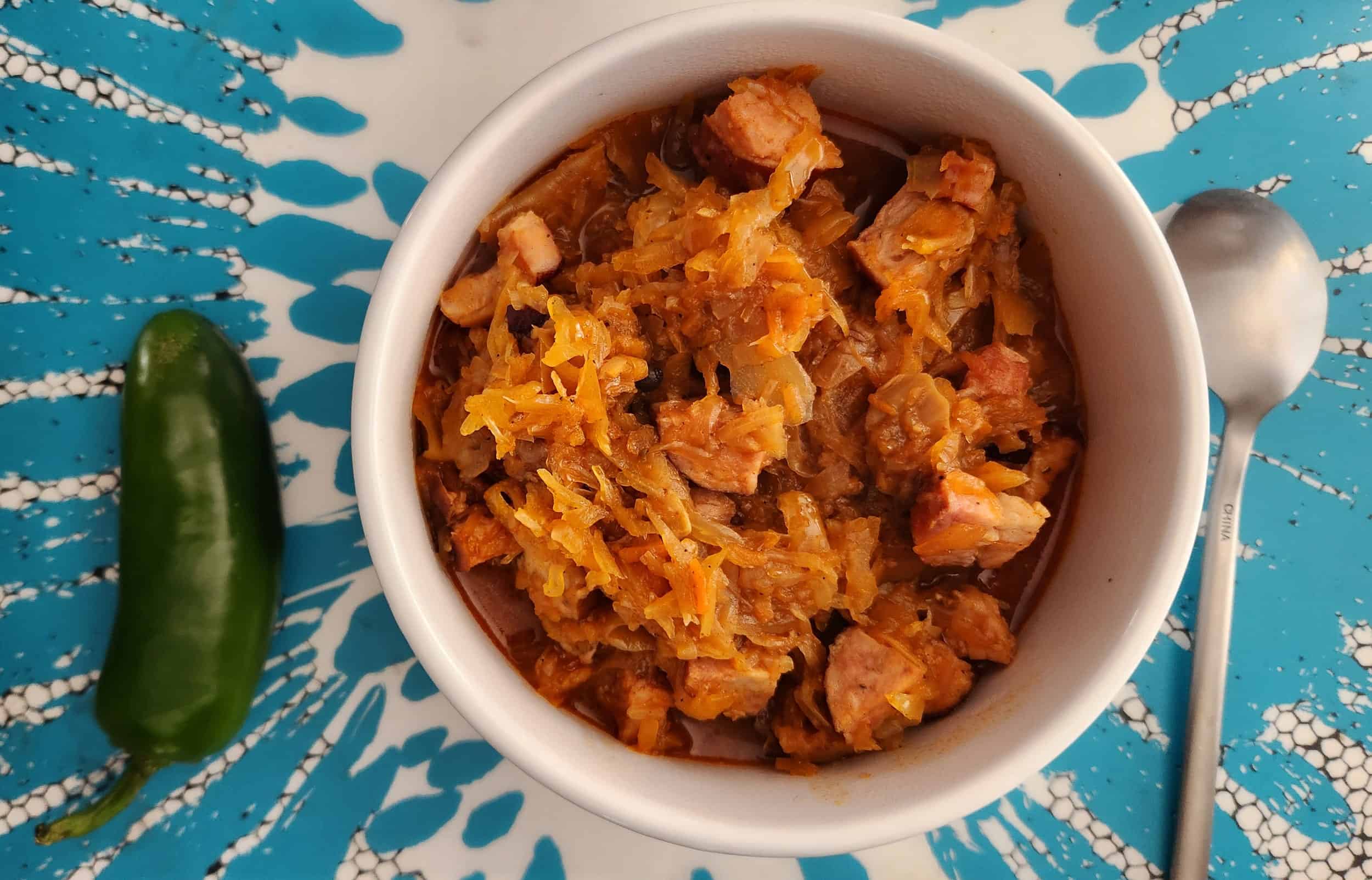 a bown of cabbage soup with a jalapano peper next to it