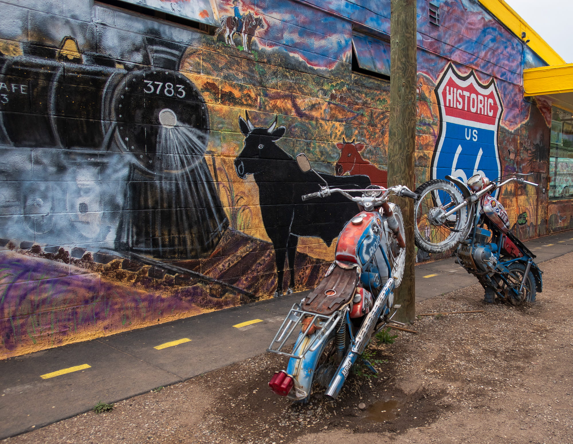 two motrocycle partially burried in front of a mural